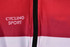 A red and white cycling jersey featuring a zip and a logo. Suitable for team wear in cycling sports.
