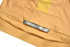 A close-up of a yellow sports jersey featuring mesh detailing and a branding label at the bottom.