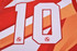 A red and orange sports jersey featuring the number 10, with a logo on the fabric.