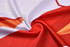 A close-up of a red and white sports jersey fabric, featuring a smooth, swirling texture with graphic patterns.