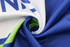 A close-up of a blue and white sports uniform fabric, featuring a swirl of material with a green inner lining and a logo.