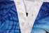 A blue and white sports uniform featuring a buttoned neckline and a vibrant design, with a logo present.