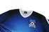 A blue and black soccer jersey featuring a logo with a football design. The shirt has a V-neck and is predominantly blue.