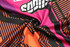 A custom BMX T-shirt featuring a vibrant design with pink, black, and orange patterns, along with branding.