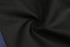 A close-up of black fabric with a smooth texture, featuring a swirl pattern. The image also includes a hint of navy.