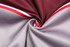 A fabric swirl showcasing a reversible varsity jacket in maroon and grey with red accents.