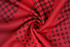 A red fabric with a textured pattern of circles and squares, featuring a smooth, swirling design.