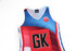 A brightly coloured netball dress featuring blue, red, and white designs, with a black logo and a large "GK" on the front.