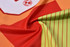 A vibrant football jersey featuring a blend of orange, red, and green colours with a logo.