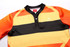 A rugby tee in vibrant orange, yellow, and black stripes with a collar and a logo on the chest.