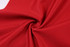 A close-up of red fabric featuring a textured pattern, suitable for rugby uniform women’s shorts, with a logo present.