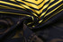 A close-up of a fabric featuring bold black and yellow patterns, designed for a rugby top.