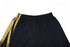 Black sports shorts with a patterned gold side stripe and an elastic waistband. Features a logo.