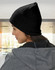A beige cable knit beanie with a fleece headband, worn on a person’s head, seen from the side.