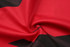 A close-up of red and black fabric with a smooth, swirling texture, featuring abstract patterns.
