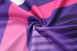 A vibrant fabric featuring a mix of purple, pink, and white patterns, showcasing a smooth, silky texture.