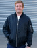 A man in a black soft shell jacket with a zip-up front and side pockets, standing against a grey background.