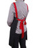 A black canvas bib apron with red straps tied at the back, worn by a person in a checkered shirt.