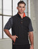 A men's softshell vest in black with orange accents, featuring a zip front and side pockets. It has a logo on it.