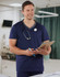 A men's short-sleeve scrub top in navy blue with a contrast colour neckline and a pocket, featuring a stethoscope.