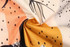 A close-up of fabric featuring a vibrant pattern with peach, orange, black, and cream colours, showcasing a light texture.