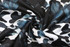 A patterned fabric featuring dark blue and black foliage against a white background, with a smooth texture.