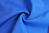 A close-up of smooth, blue fabric arranged in a spiral, showcasing its texture and colour.