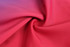 A close-up of smooth fabric in vibrant shades of red, featuring a twist pattern. 