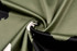 A close-up view of camouflage fabric featuring shades of green, black, and beige. The material is textured.