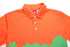 An orange polo shirt with a green foliage design and a collar, featuring buttons and a logo inside the collar.