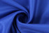 A blue fabric with a smooth texture and subtle weave, featuring a spiral fold.