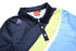 A polo shirt in navy, light blue and green with a logo on the left side and three buttons down the front.