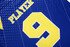 A blue polo shirt featuring a large yellow number 9 and the word "PLAYER" above it, with a logo present.