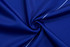 A close-up of blue fabric featuring a smooth texture with a white trim. It has a logo in one corner.