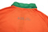 An orange sports polo with a green collar and a small logo on the back.