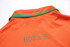 An orange polo shirt with a green trim on the collar and a logo on the back.