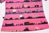 A pink sublimated polo featuring a skyline design with silhouettes of famous landmarks against a sunset background.
