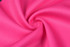 A vibrant pink fabric with a textured surface, showcasing a smooth, swirling pattern. The material appears lightweight and breathable.