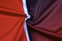 A close-up of a fabric featuring red, burgundy, and black colours with a white stripe, likely for a customised polo.