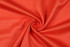 A vibrant red fabric with a textured surface, featuring a smooth and flowing appearance.