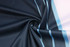 A fabric with a navy blue base and light blue stripes, arranged in a swirling pattern. It has a smooth texture.