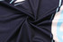 A close-up of a folded navy polo shirt featuring light blue accents and a logo.