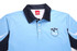 A light blue sublimated shirt with a black collar, featuring a logo on the front.