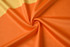 An orange fabric with a smooth texture, featuring a swirl pattern.