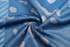 A blue Aboriginal singlet vest featuring a patterned design in lighter shades, showcasing the fabric's texture.