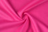 A textured fabric in vibrant pink, featuring a smooth, stretchy weave. It has a light and breathable appearance.
