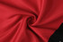 A red and black fabric material, with a textured pattern, twisted to show its softness and flexibility.