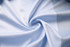 A light blue fabric, smooth and silky, arranged in a swirling pattern, showcasing its soft texture.