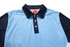 A polo shirt in light blue with a navy collar and sleeves, featuring three buttons and a logo on the front.