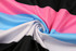 A swirl of fabric featuring stripes in black, white, pink, and blue. The texture displays a sporty pattern with a sheen.